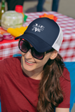 Woman wearing an Ethi-Cali navy blue and white vegan trucker hat on a summer day