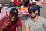 Two men wearing Ethi-Cali vegan trucker hats at a plant based bbq on a summer day